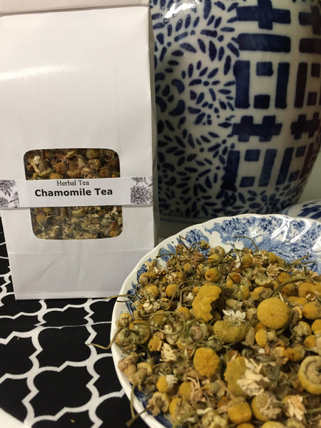 chamomile tea in a white bag with chamomile flowers surrounding the bag