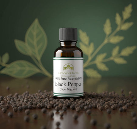 Bottle of 100% Pure Essential Oil Black Pepper on a decorative gold tray with black peppercorns.