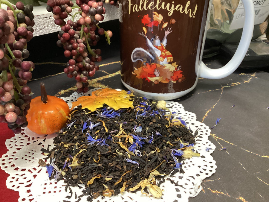 Tea leaves with a decorative mug featuring a colorful design on a black surface.