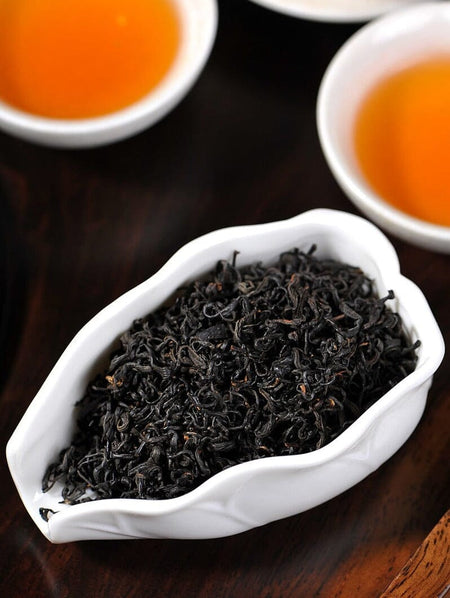 black tea in a with dish with a cup of warm tea 