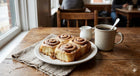 Plate of cinnamon rolls with a cup of coffee on a wooden table.