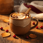 Rustic ceramic mug of steaming hot apple cider with a cinnamon stick, warm wooden surface, soft autumn light
