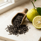 Loose black tea spilling from a wooden scoop beside whole and halved bergamot citrus