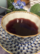 picture of  the prepared tea in the blue and gold cup. Very dark red and brown color.