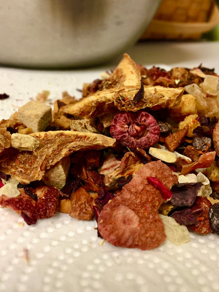 Fruit loose rooibos showing dried strawberries, and raspberries with orange  slices and rooibos on white table cloth