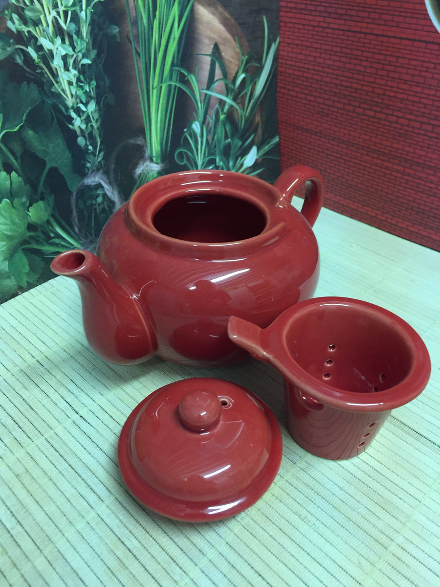 red ceramic teapot with lid off and ceramic infuser shown