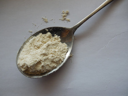 Silver spoon holding a tablespoon of beige powder