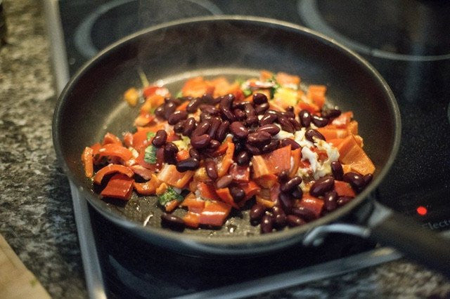 beginnings of chili in a pan with peppers, beans onions